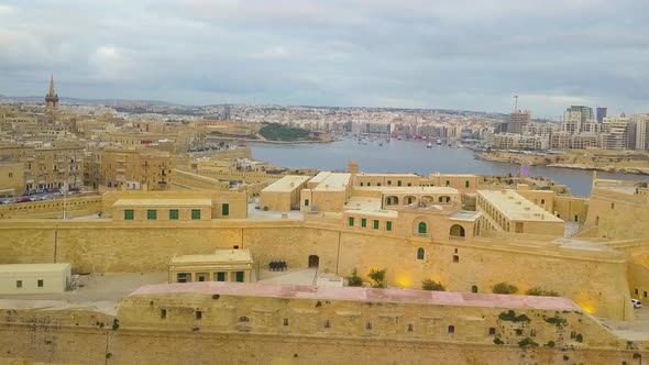A drone flying along the Grand Harbour from Fort St Elmo towards the Bell Monument at Barrakka Garde