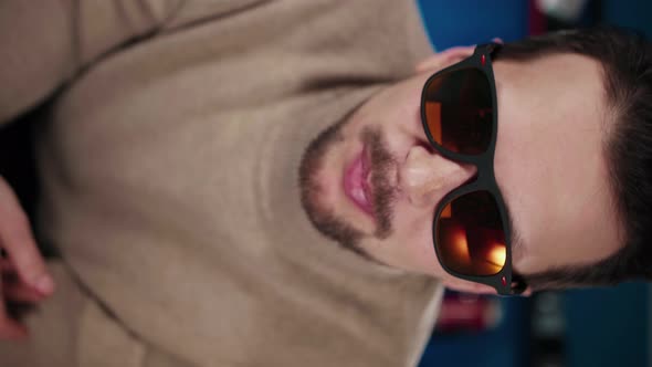 A European Man in Sunglasses Sits at a Table in the Studio and Says Something