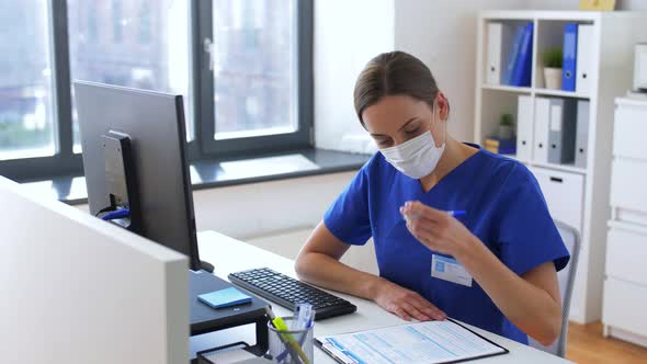 Doctor or Nurse in Mask with Clipboard at Hospital