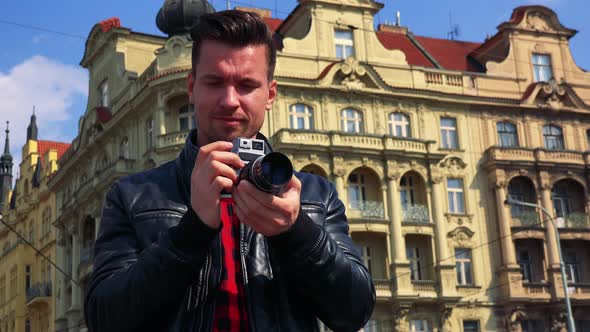 A Young Handsome Man Takes Photos with a Camera - Closeup From Below - an Old Yellow Building
