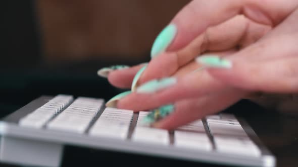 Fingers of a Young Girl are Typing on the Keyboard of a White Laptop