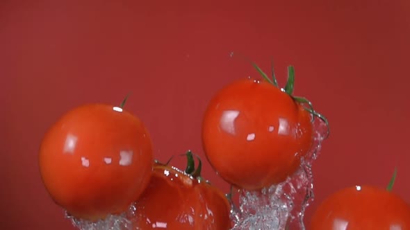 Red Cherry Tomatoes are Flying Up on the Red Background with the Splash of Water