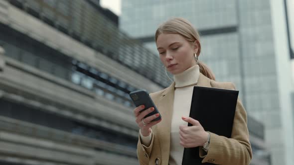 Lady Carrying Clipboard and Mobile in Hands Outdoors