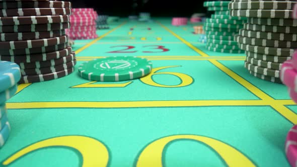 Camera Pans Over Green Gaming Table with Stacks of Casino Chips on Black Background