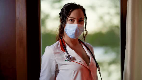 Dolly in View of Young Female Doctor or Nurse Wearing Surgical Face Mask and White Gown and Looking