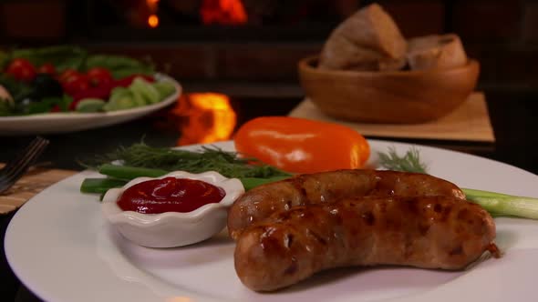 White Plate Full of Grilled Sausages on the Background of a Burning Fireplace