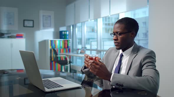 Portrait of AfricanAmerican Civil Servant Work on Laptop and Drink Tea