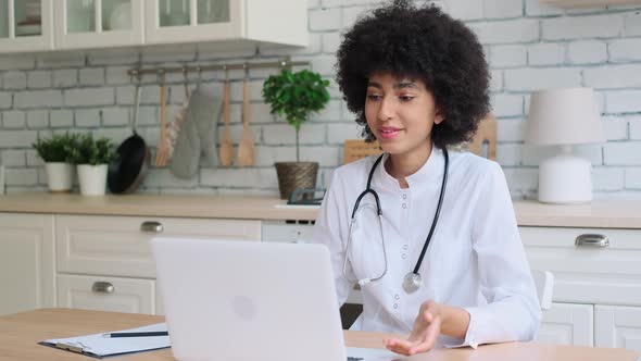 Afro American Woman Doctor in Dressing Gown Uses Laptop During Online Consultation at Home