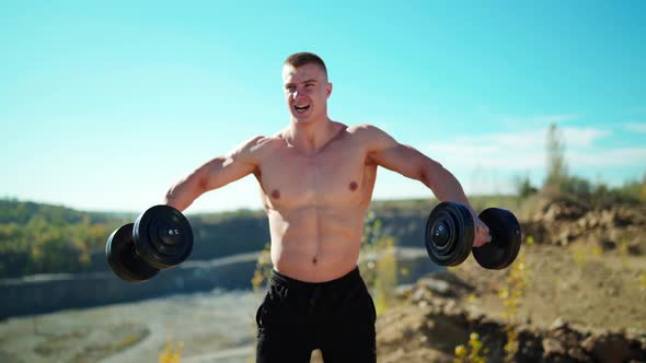 Portrait of concentrated sportsman lifts dumbbells. 