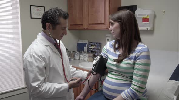 Doctor taking a pregrant woman's blood pressure.