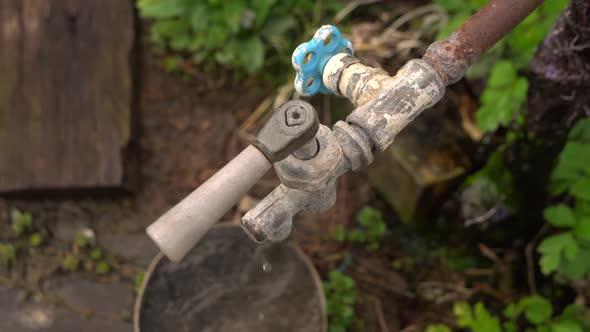 Water From the Tap Drips Into the Old Saucepan