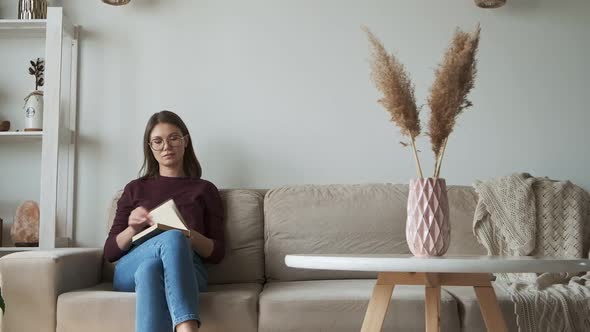 Woman Reading Book Sitting in Sofa at Home