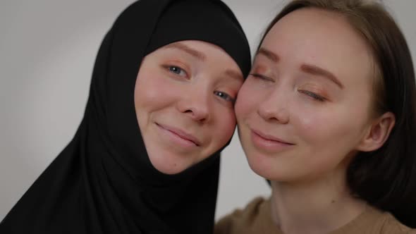 Closeup Faces of Twin Sisters Looking at Camera Smiling Posing at Grey Background