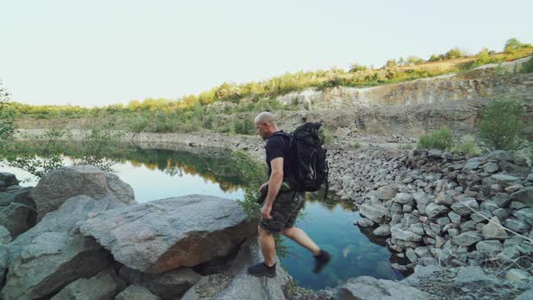 A tourist in summer clothes walks on the edge of a quarry with huge stones