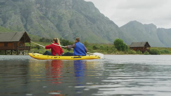 Caucasian couple having a good time on a trip to the mountains, kayaking together on a lake