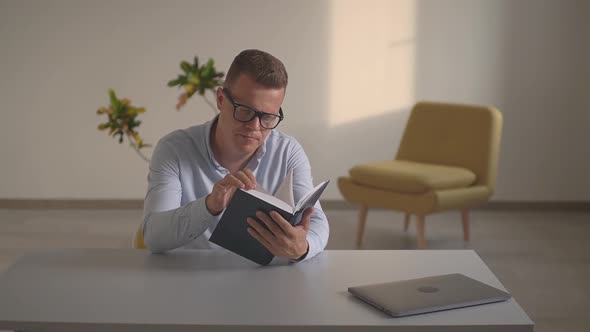 a Man in the Office Reading a Book