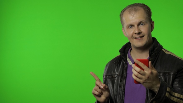 Rocker Man Showing Side Advertising Area. Using Smartphone, Pointing at Wall for Your Text, Logo