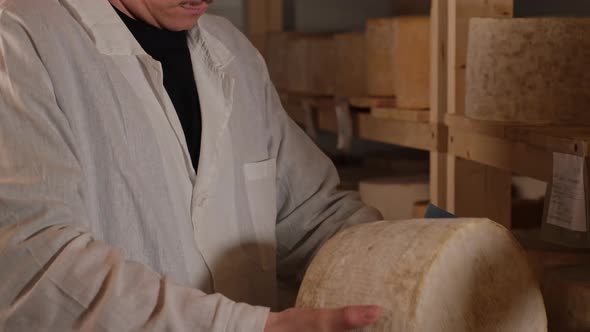 Handsome Young Cheese Maker in Uniform Checking the Seasoning of Cheese