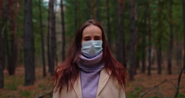 Portrait a Beautiful Woman in a Medical Mask is Standing in the Forest