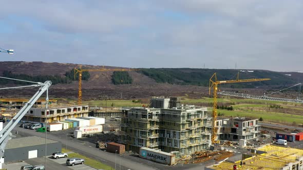 Multiple Tower Cranes Erected Beside Constructed Buildings During The Day. Aerial Shot