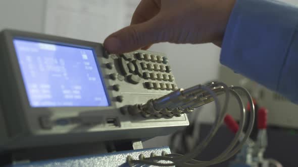 worker adjusts an electronic measuring instrument in a laboratory for testing