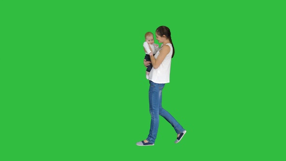 Young Mother Holding Her Baby in Hands and Walking On