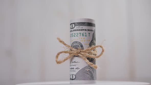 Stack of Hundreddollar Bills Tied with a Rope Rotates on a Light Background