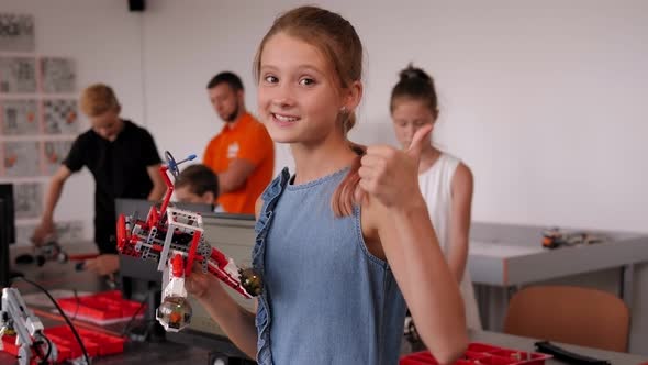 Portrait of a Girl Student in Robotics Office at School with Robot in Her Hands.