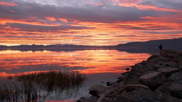 Silhouette of person taking photos of colorful sunset at Utah Lake