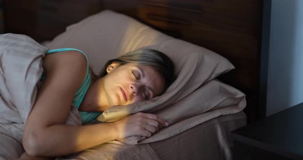 Happy Joyful Woman Wakes Up with First Rays of Sun in Bed