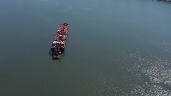 A drone view of a large red barge anchored in the Hudson River in NY on a sunny day. The camera alre