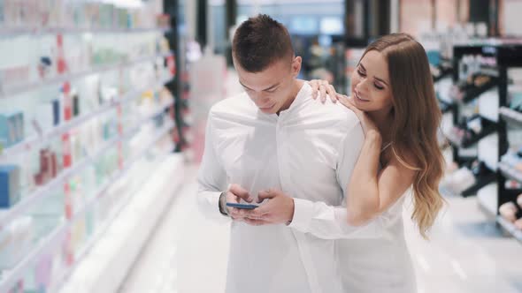 Charming Girl Asks Her Boyfriend Chatting in Smartphone To Go Shopping 