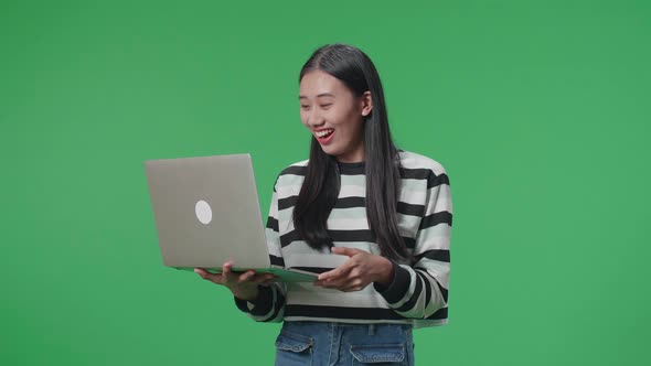 A Smiling Asian Woman Saying Wow While Using Computer On The Green Screen Background