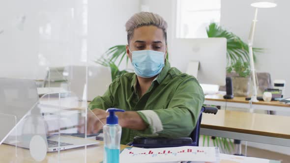 Man wearing face mask reading a document at office