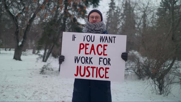 Man Showing Off a Banner Which Says If You Want Peace Work For Justice. Protest