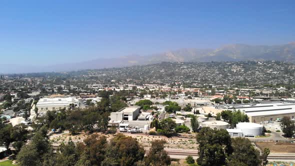 Aerial shot flying over the city buildings and luxury homes with mountains in the distance in downto