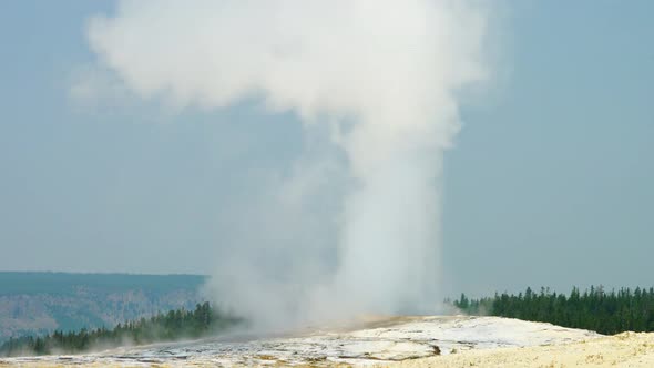 Old Faithful Geyser in Yellowstone National Park ejecting hot steam water