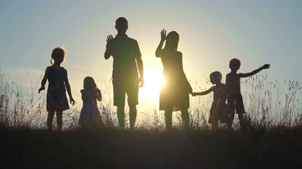 Happy Parents with Children Waving Hands at Sunset.