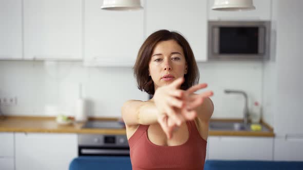 Woman Twisting Her Arms Practicing Yoga at Home Front View