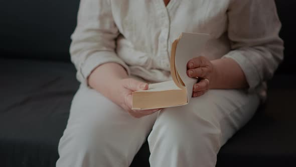 Elder Person Holding Fiction Book to Read and Relax on Sofa