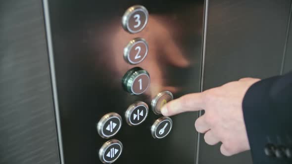 Forefinger pressing alarm button in elevator