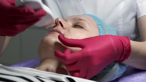 Close-up of professional beautician skin treatment with ultrasonic machine. Slow motion.