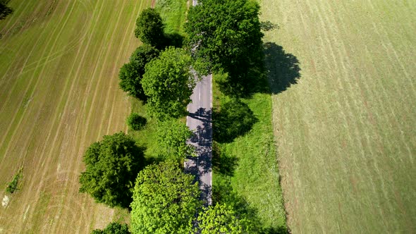 Peaceful farmland, rural country road. Drone pulls back, as cars drive