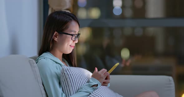 Woman drink of water and use of mobile phone at night inside living room