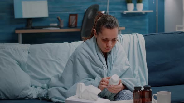 Person with Cold Reading Label of Bottle with Capsules and Pills