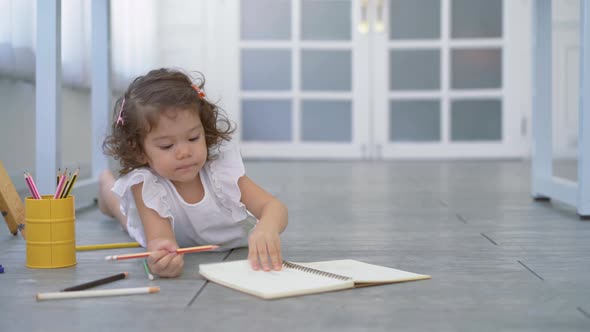Cute Little girl writing on a notebook lying floor, learning concept at home	