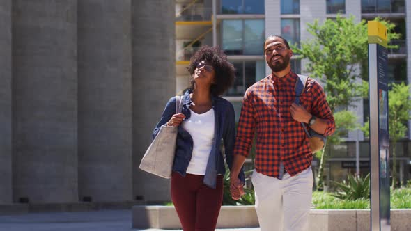 Diverse couple walking on the street holding hands smiling and talking