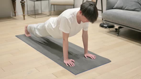 Tired Asian Man Doing Pushups on Yoga Mat at Home