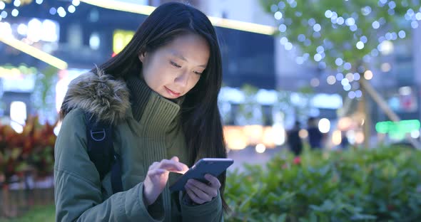 Woman using mobile phone in the city at night