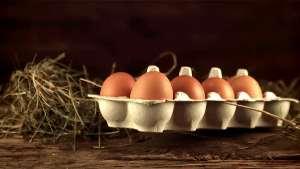 Super Slow Motion Cardboard Box with Raw Eggs Falls on the Table